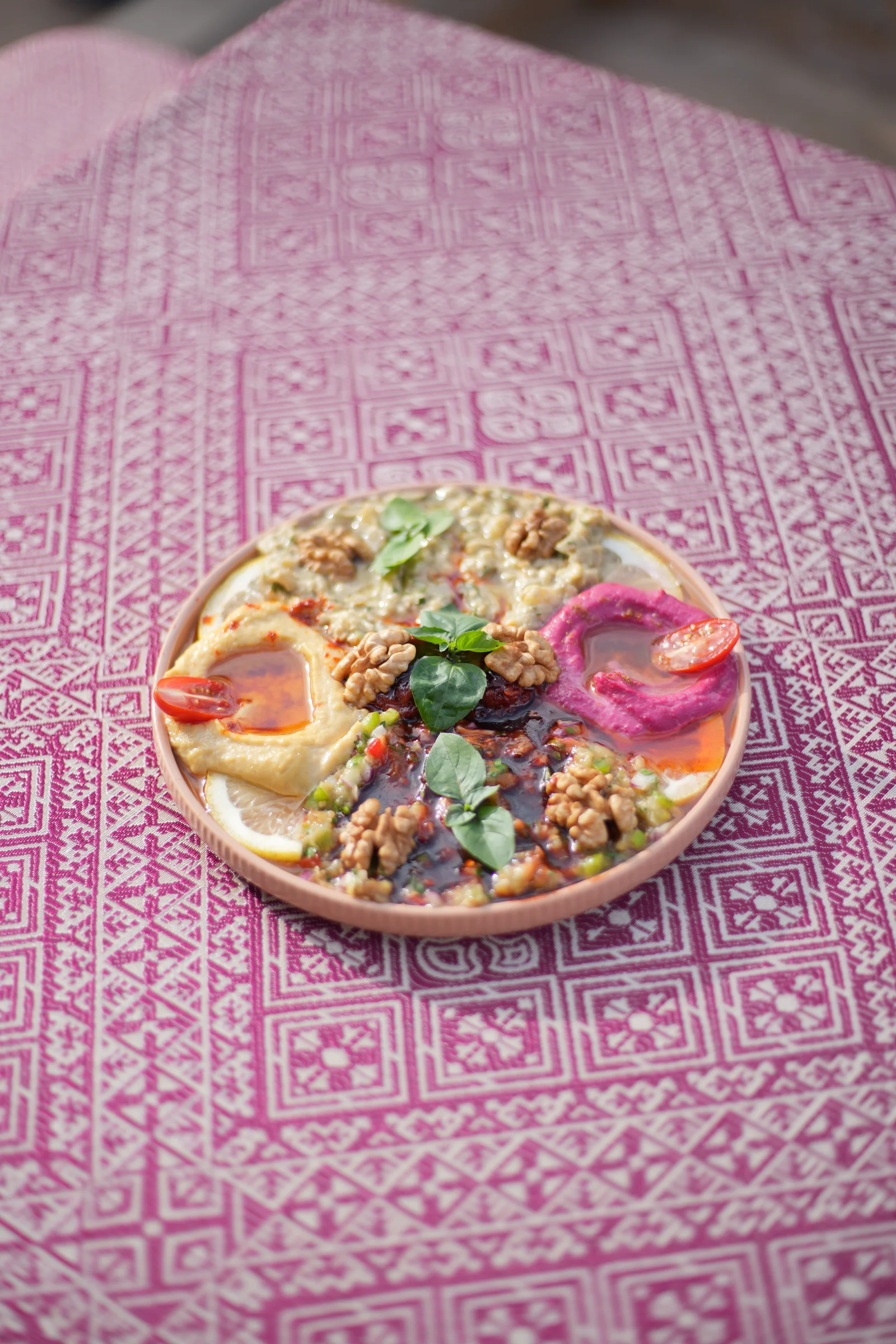 Salade colorée dressée dans une assiette sur une table rose