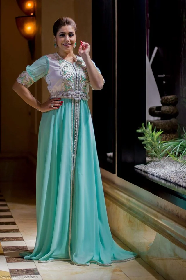 Portrait d’une femme en caftan turquoise dans un décor de riad