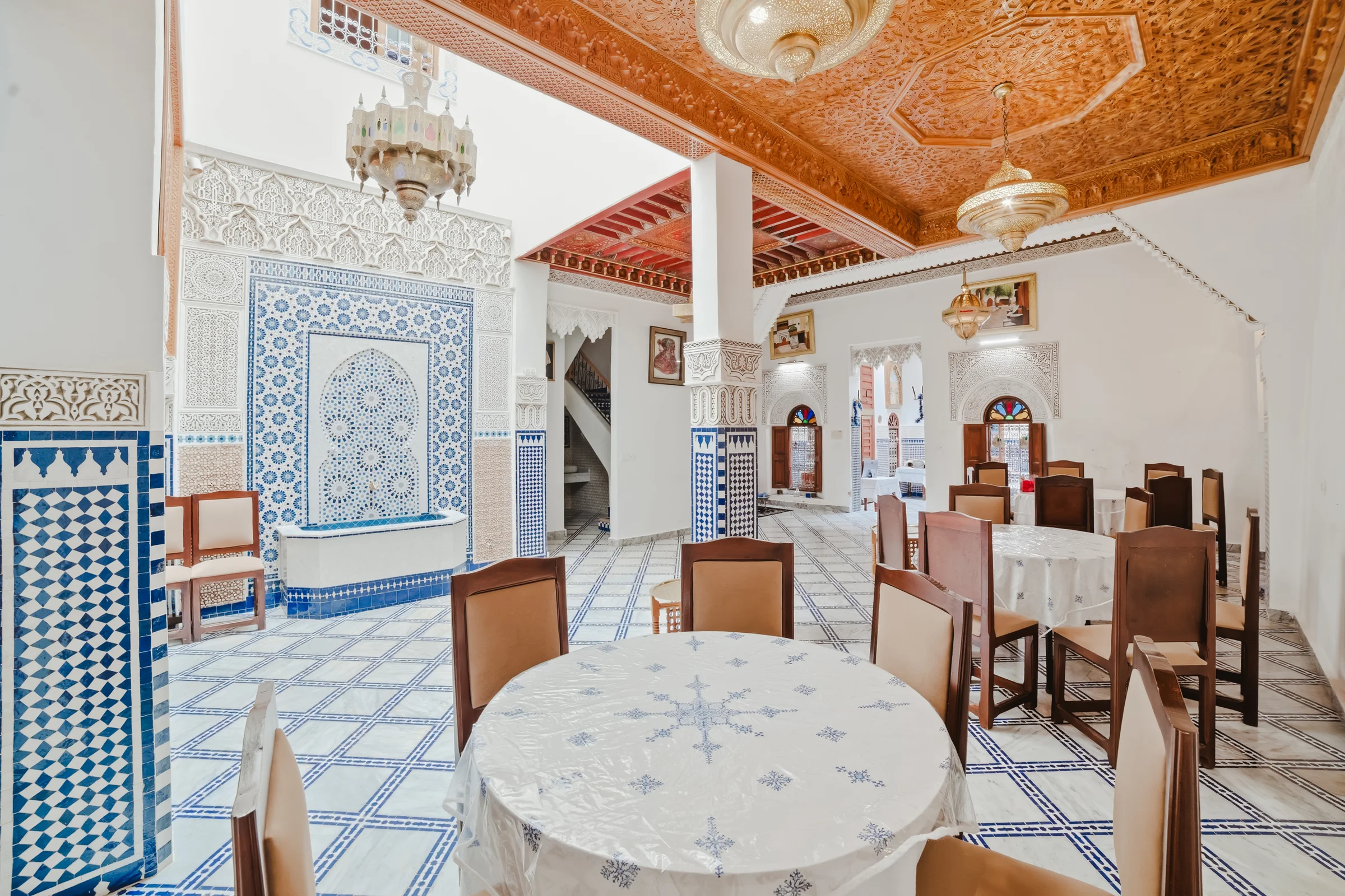 Salle à manger d’un riad avec plafond sculpté et sol en zellige