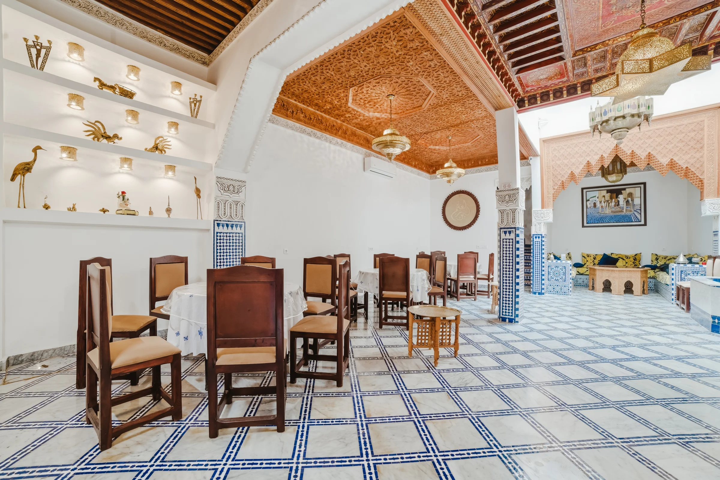 Tables and chairs beneath the decorated ceiling of a riad