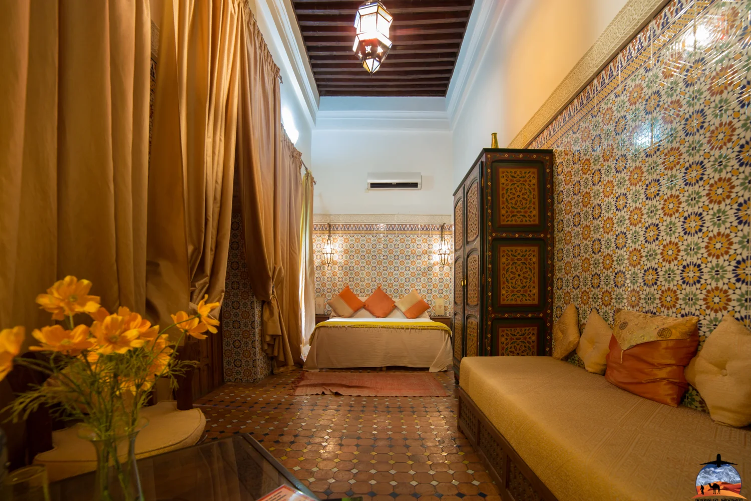 Riad sitting room with zellige walls and golden curtains