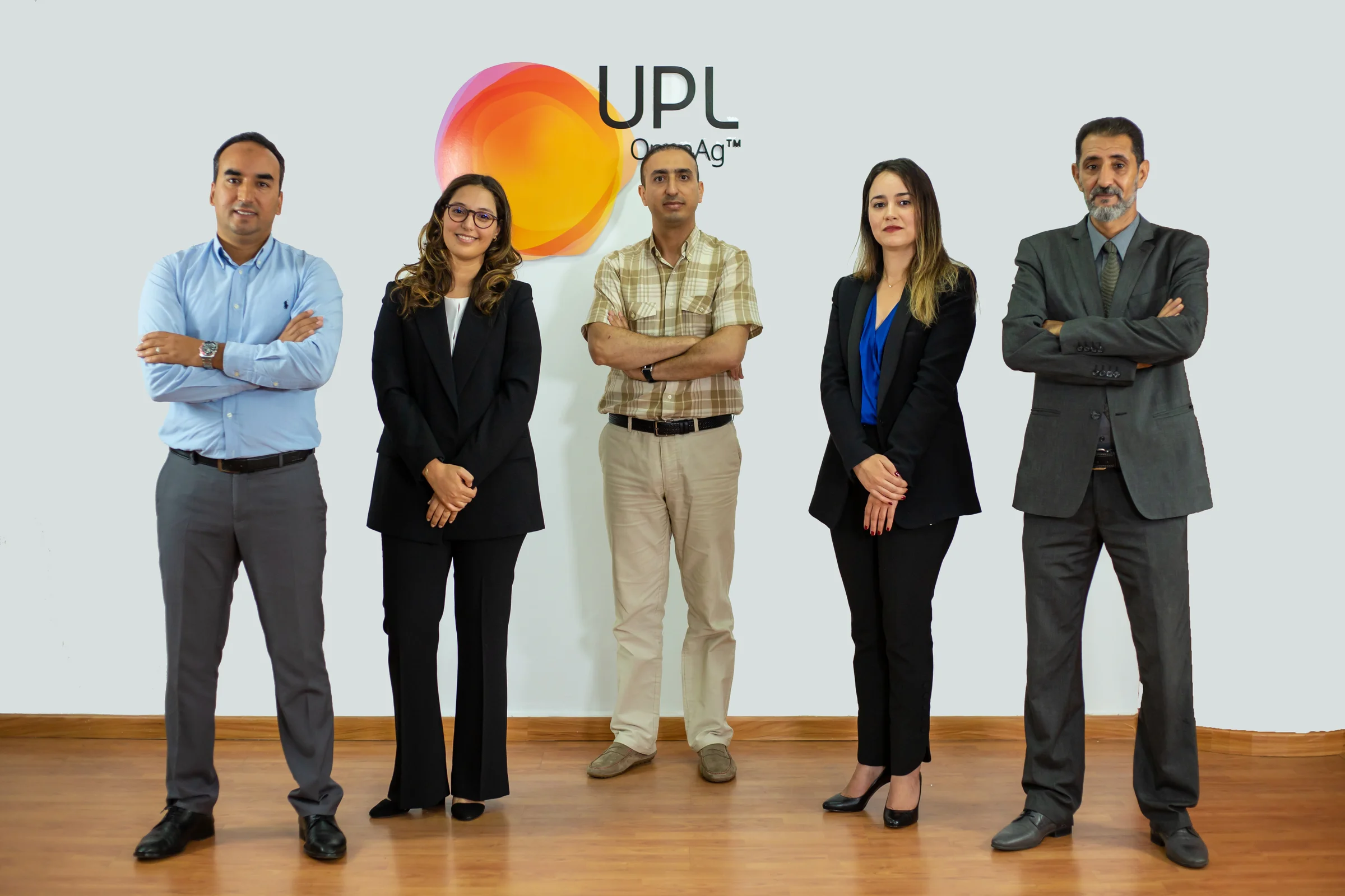 Portrait de cinq collaborateurs devant le logo UPL