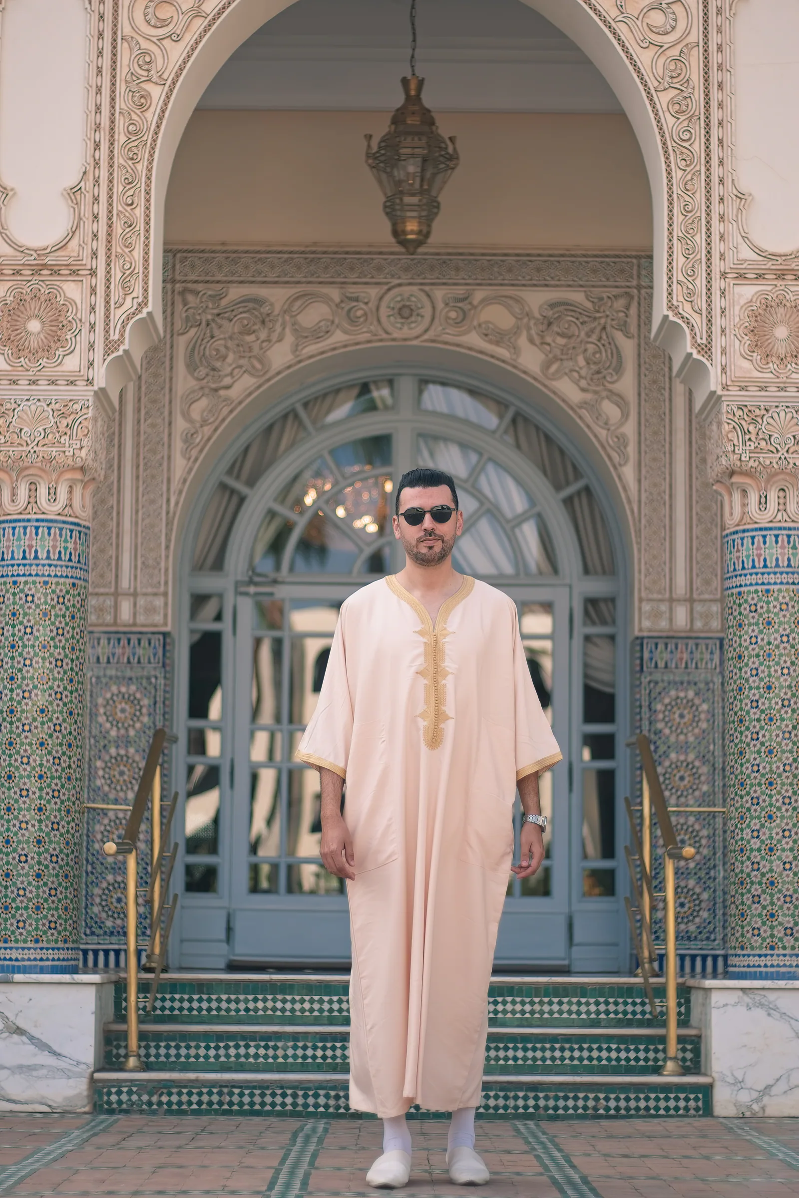 Portrait en tenue marocaine traditionnelle devant une entrée en zellige